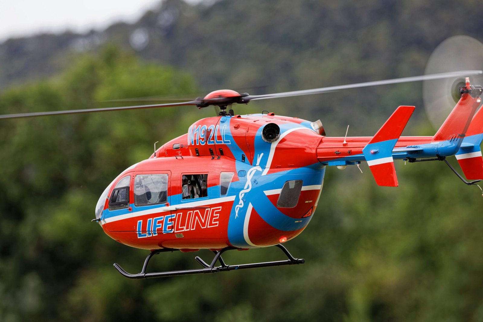 Close-up of a Lifeline helicopter in flight, showcasing its bold red and blue design.